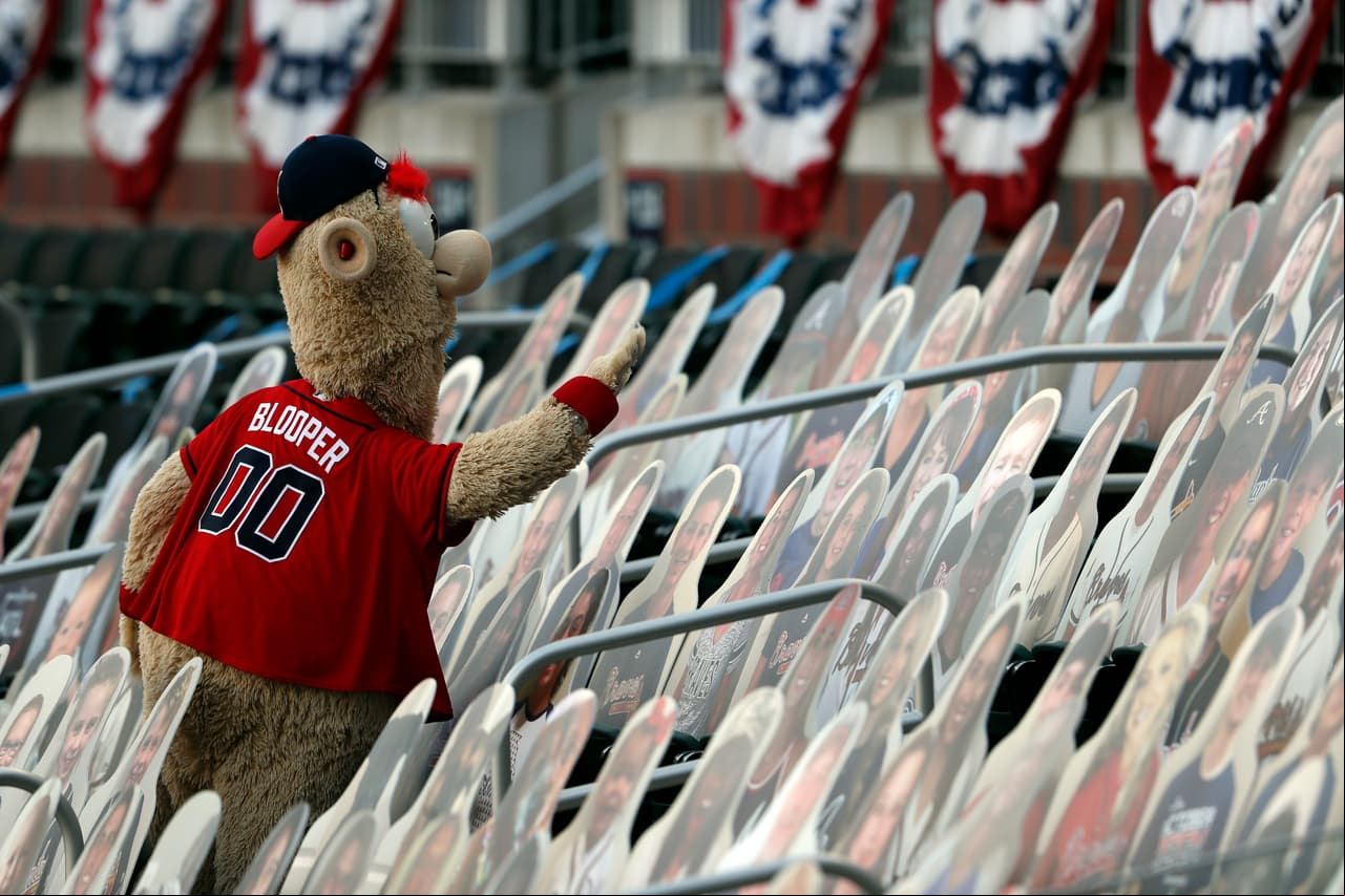La mascota de Atlanta Braves, Bloopert, trata de chocar cinco con un fanático.