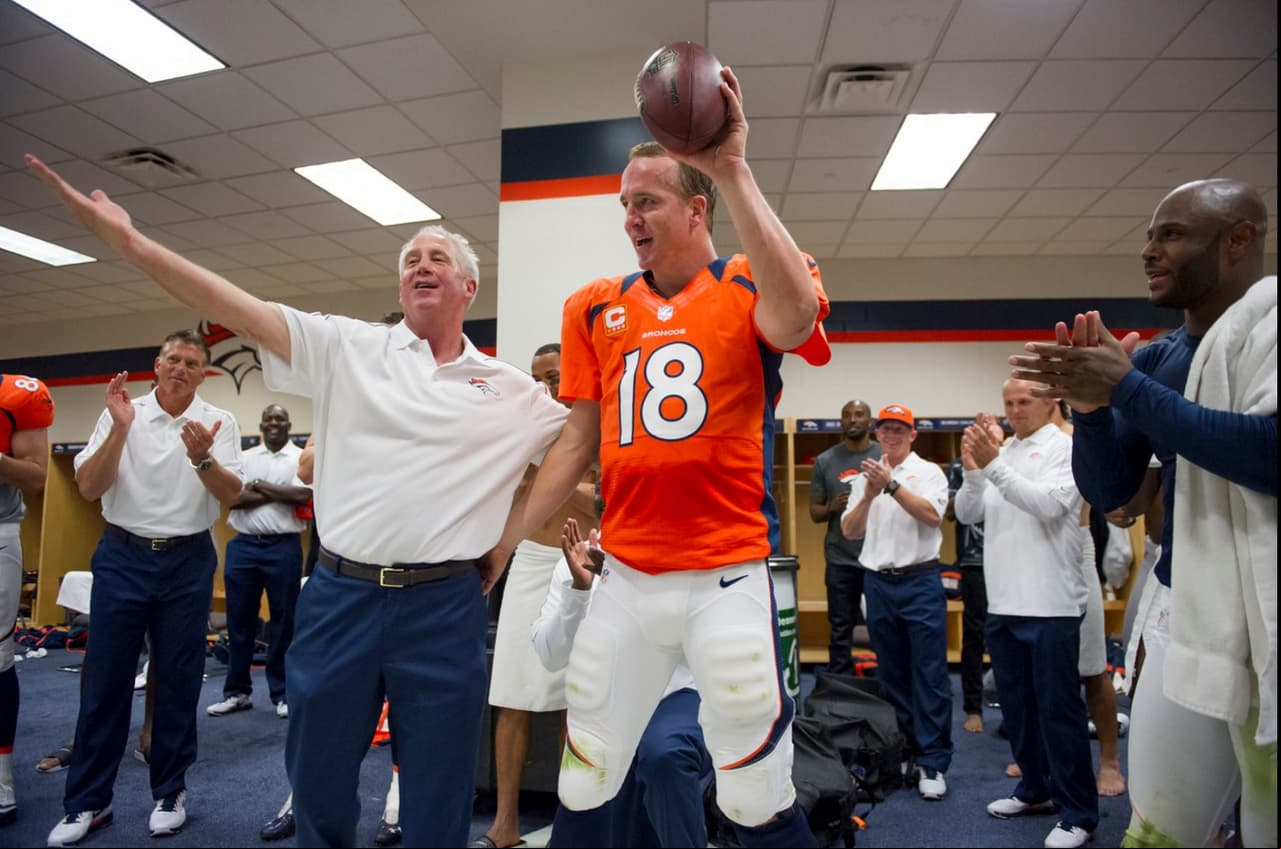 John Fox, en ese entonces HC de los Broncos, aplaudiendo la hazaña de Manning en el vestuario por sus pases de TD 400 y 401 de su carrera en 9 de septiembre del 2012.