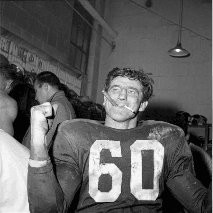 Chuck Bednarik de los Philadelphia Eagles fumando un puro en los lockers después de una victoria en contra de los Green Bay Packers. A´ño 1960.